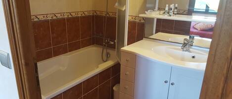 Un baño con bañera, lavamanos y espejo.