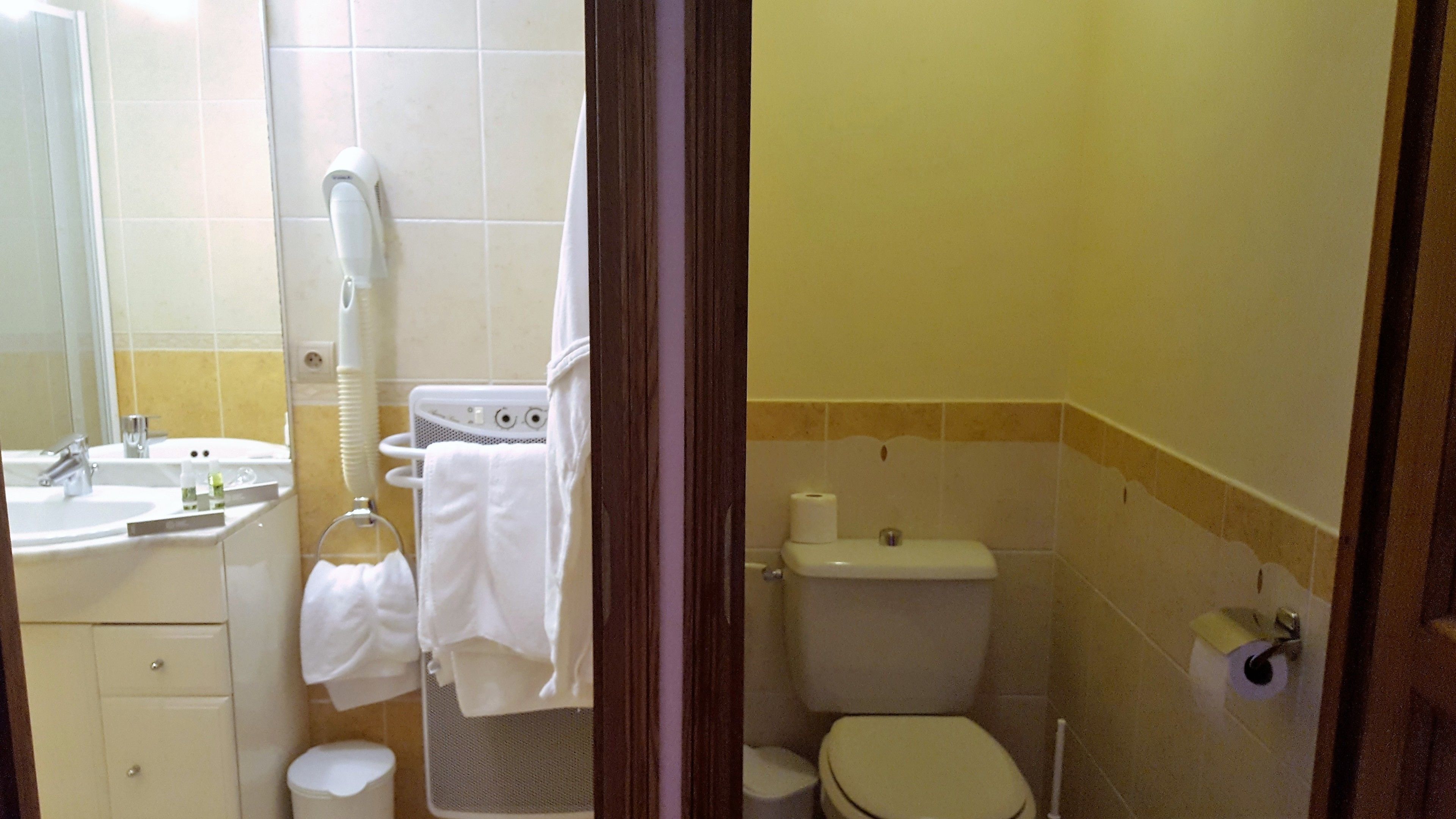 Ein kleines Badezimmer mit Waschbecken, Spiegel, Handtuchhalter und Toilette.