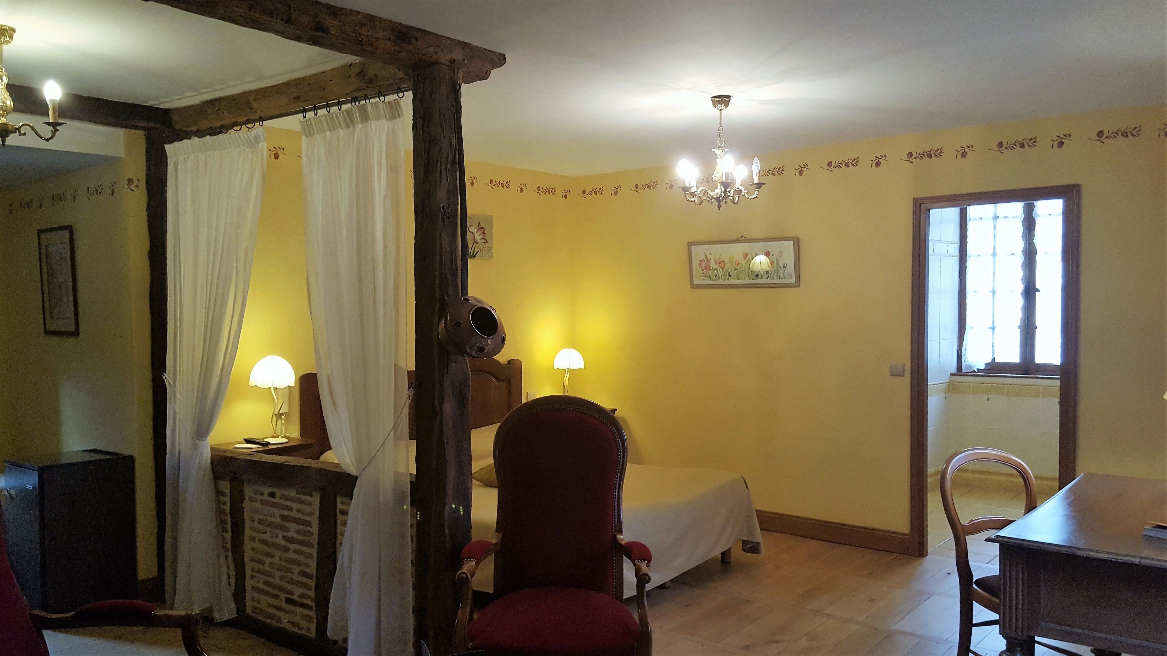 Una habitación con cama, una silla, una mesa y una lámpara.