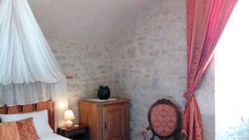 Une chambre à coucher avec un lit à baldaquin, une table de chevet en bois avec une lampe, une chaise et une fenêtre ornée de rideaux roses.