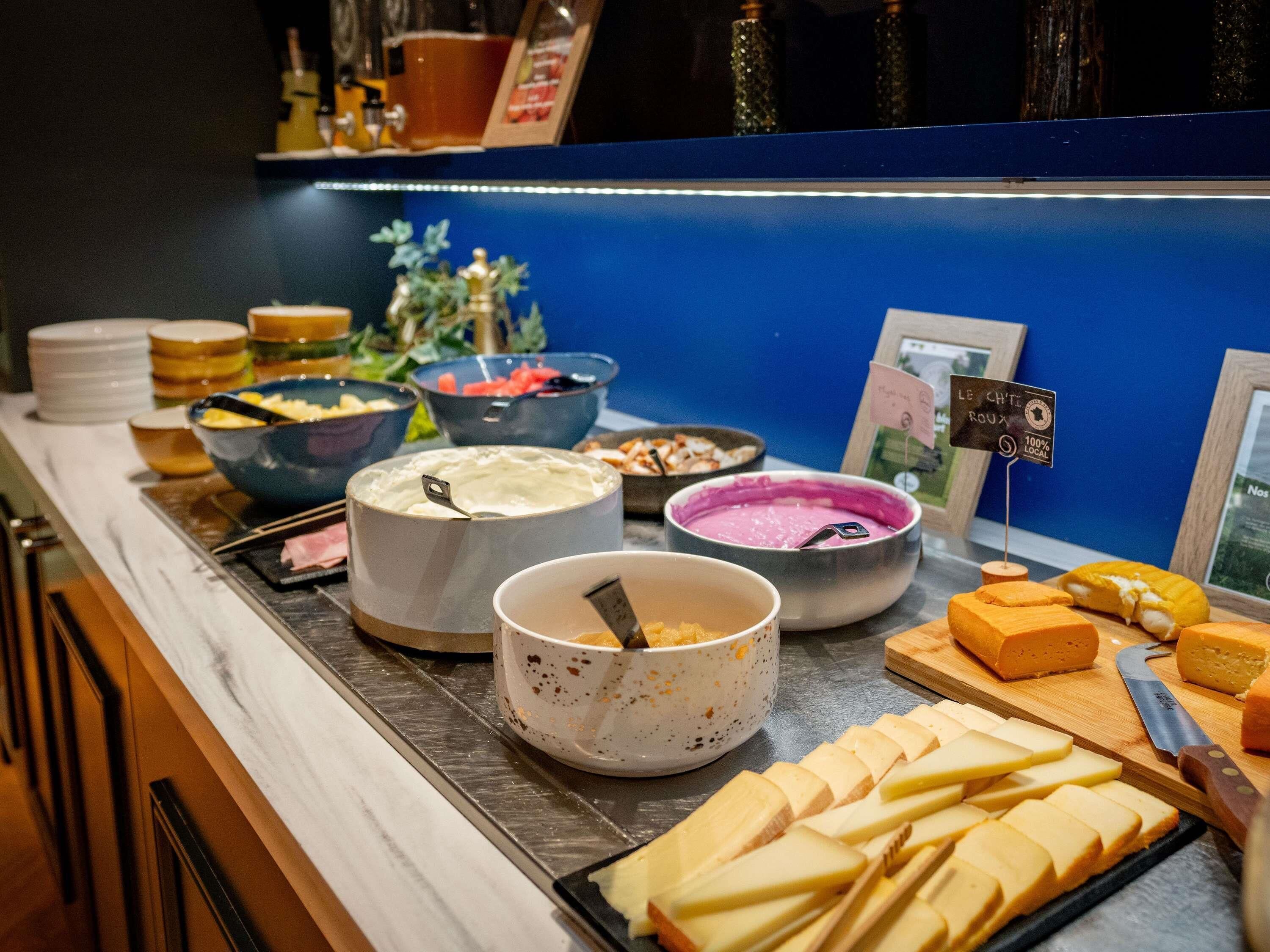 Un buffet proposant une variété de plats et une pancarte indiquant que tous les fromages sont d’origine locale à 100 %.
