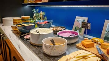 A buffet with various food items and a sign indicating 100% local cheese.