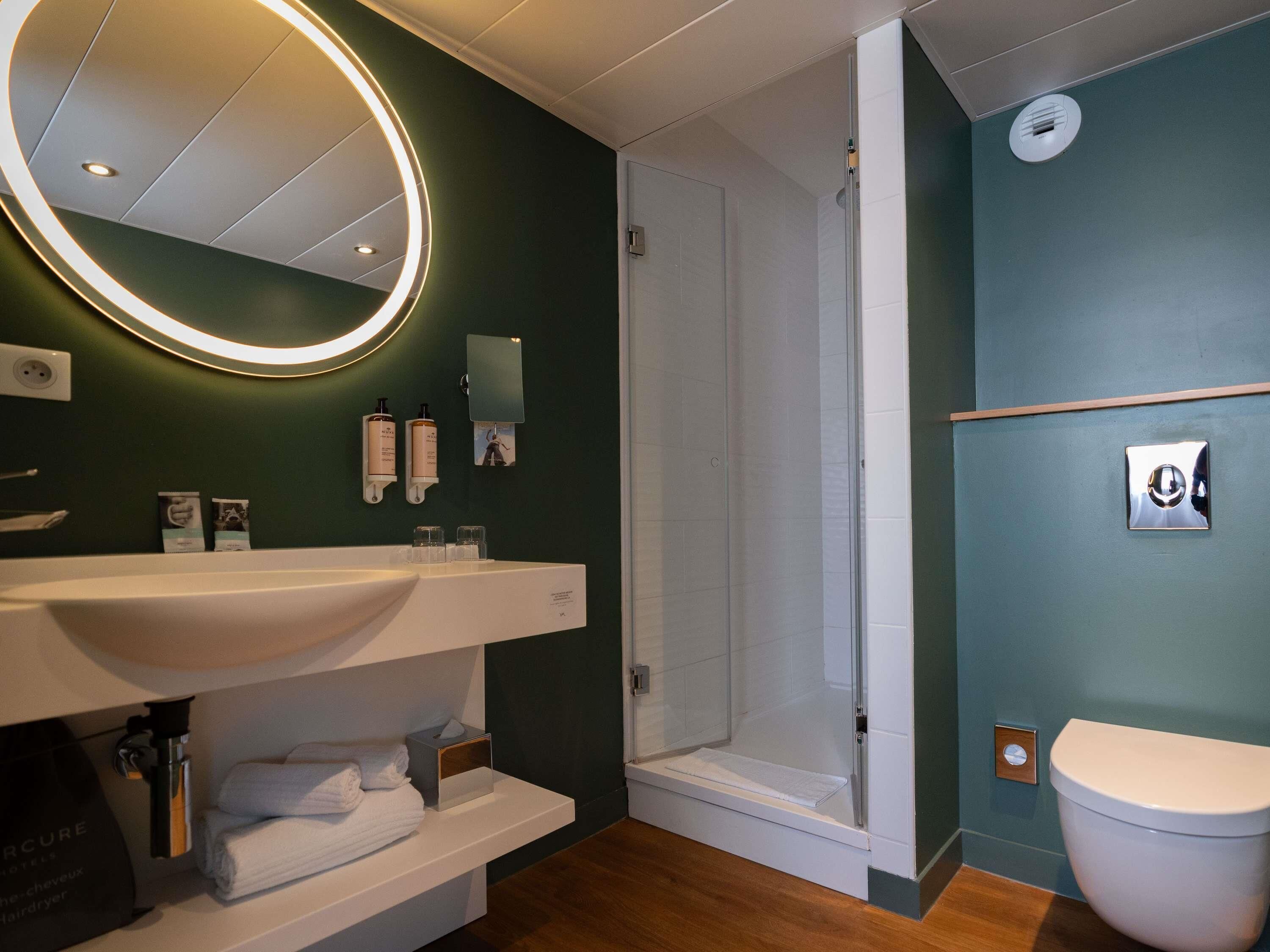 Un baño moderno con un espejo grande, un lavabo, un inodoro y una ducha.