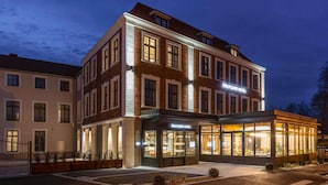 Un hotel con fachada moderna, amplias ventanas y una entrada bien iluminada.