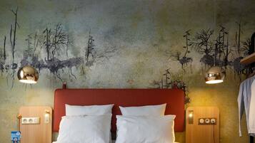 Habitación de hotel con una cama grande, dos mesitas de noche, cabecero rojo y un mural en la pared.