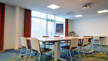 A conference room with a large table, chairs, a projector, and a presentation screen.