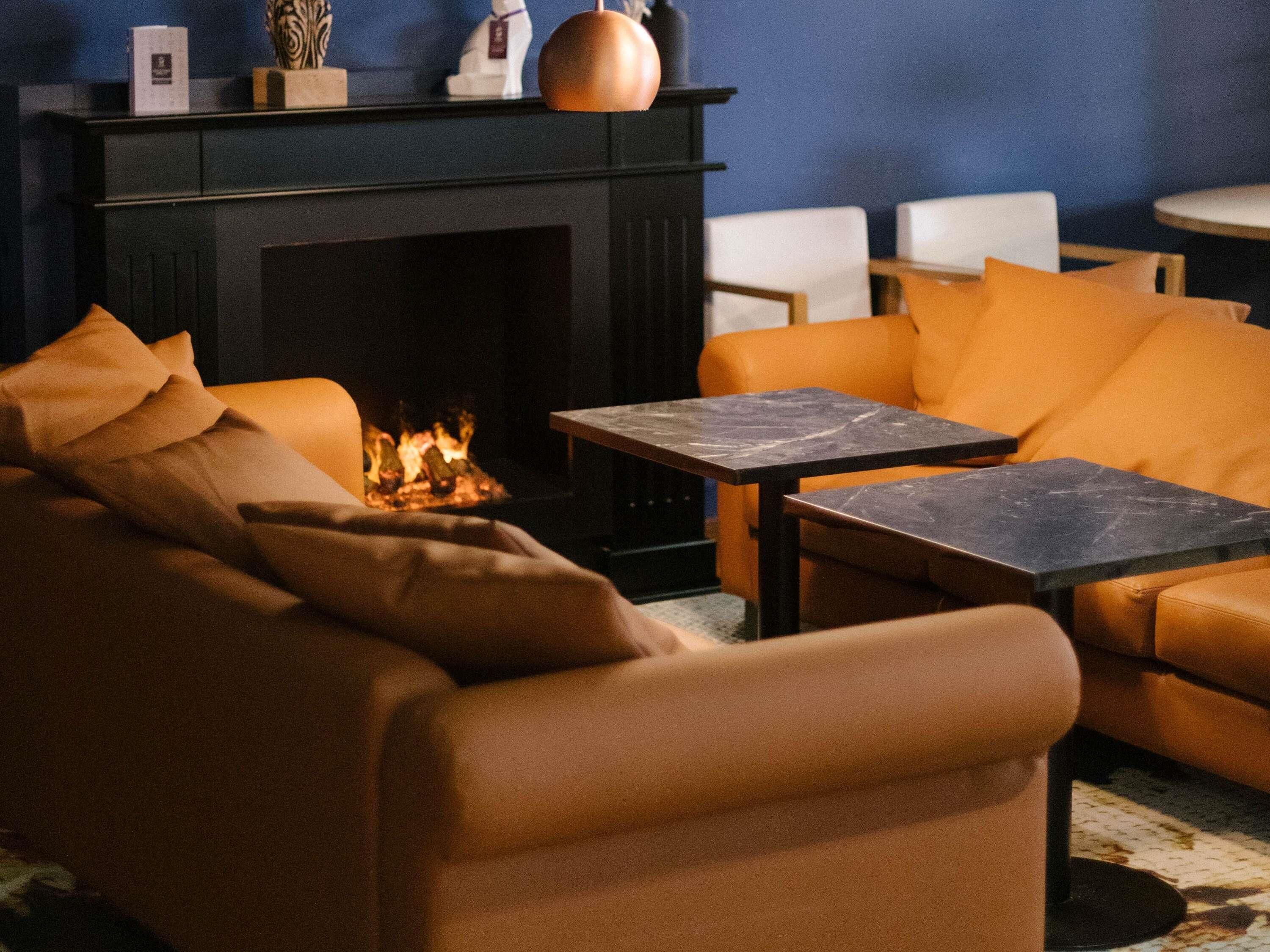 A cozy living room with a fireplace, orange sofas, and a marble coffee table.