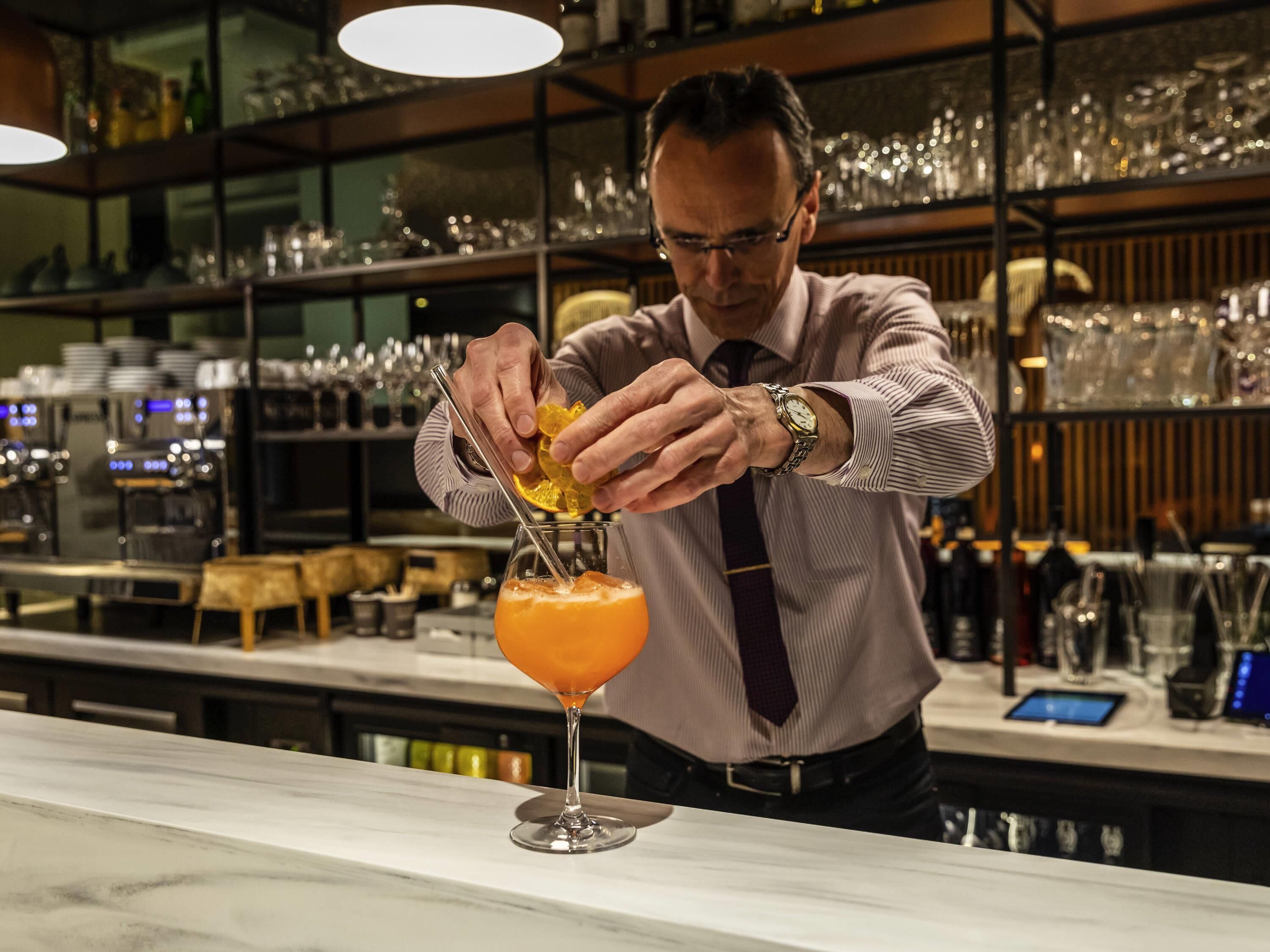 A bartender preparing a cocktail with a citrus garnish.