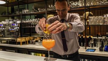 Un bartender preparando un cóctel con un adorno cítrico.