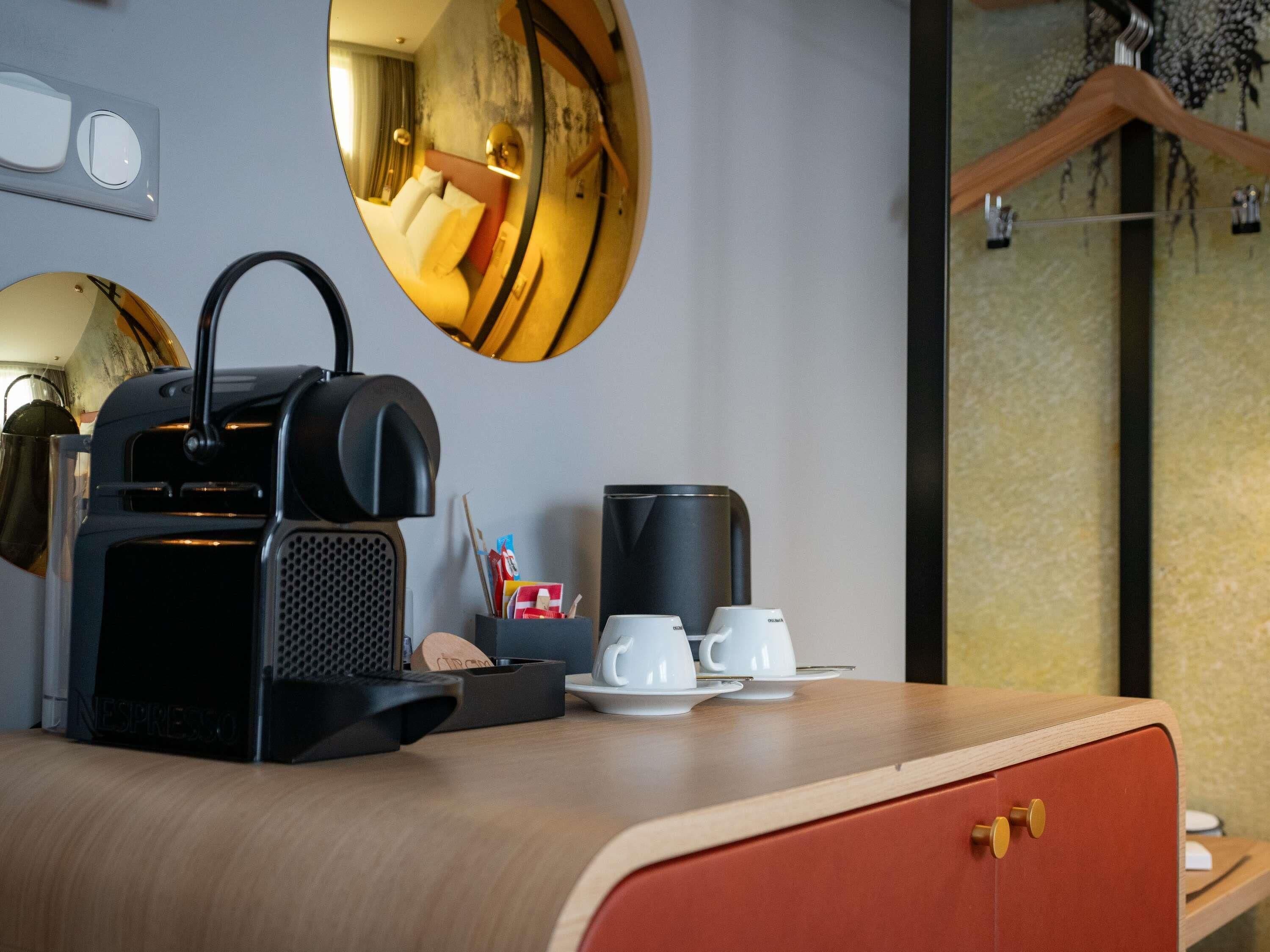 A compact kitchenette with a coffee machine, two cups, and a small tray.