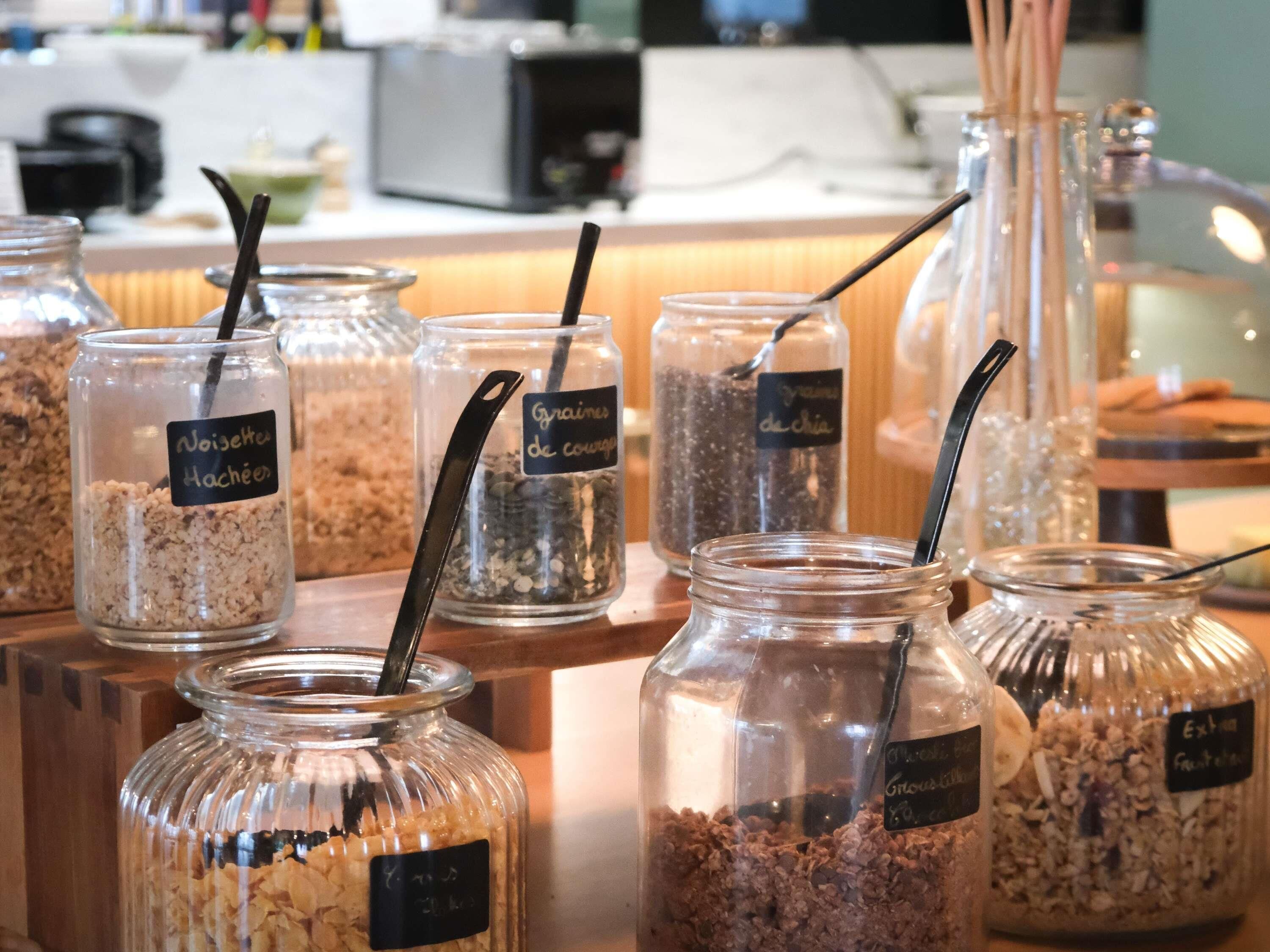 Exposició de diversos aliments en pots de vidre amb etiquetes, probablement en un café o botiga d'alimentació.