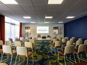 A conference room with rows of chairs, a projector screen, and a presentation about Mercure Hotels. - Mercure Saint Omer Centre Gare  (Saint-Omer)