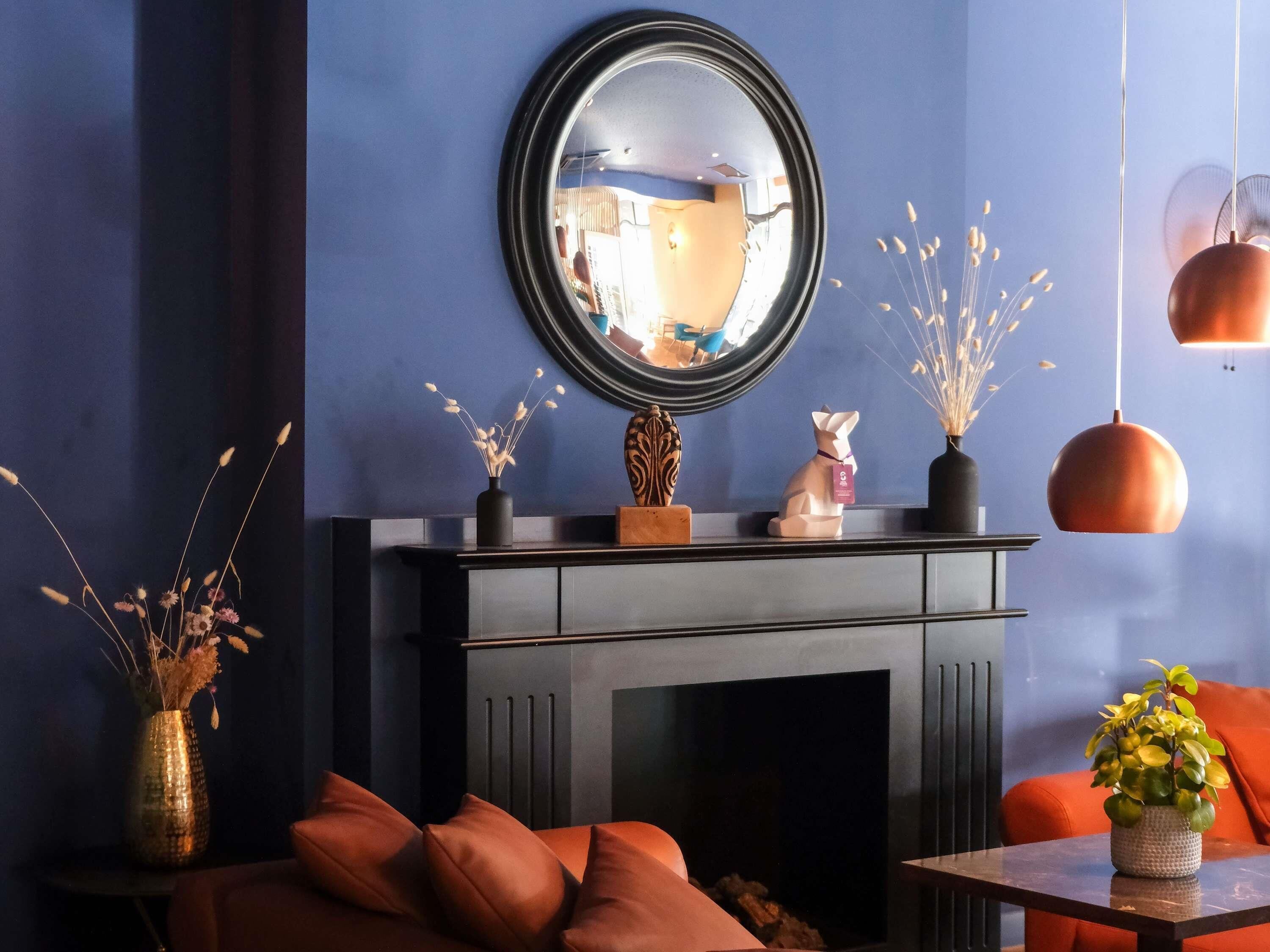 A room with a fireplace, a mirror, and a sofa.