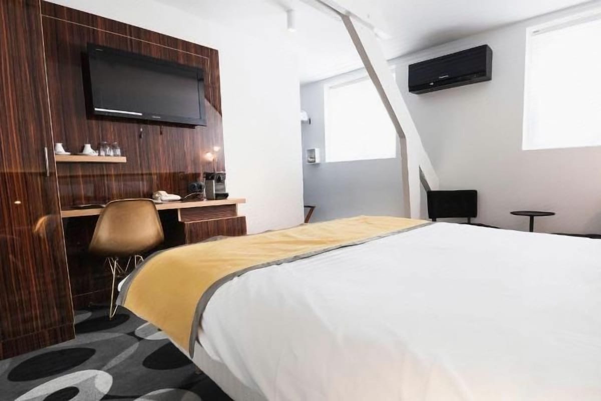 Een hotelkamer met een bed, een bureau, een stoel, een televisie en een raam.