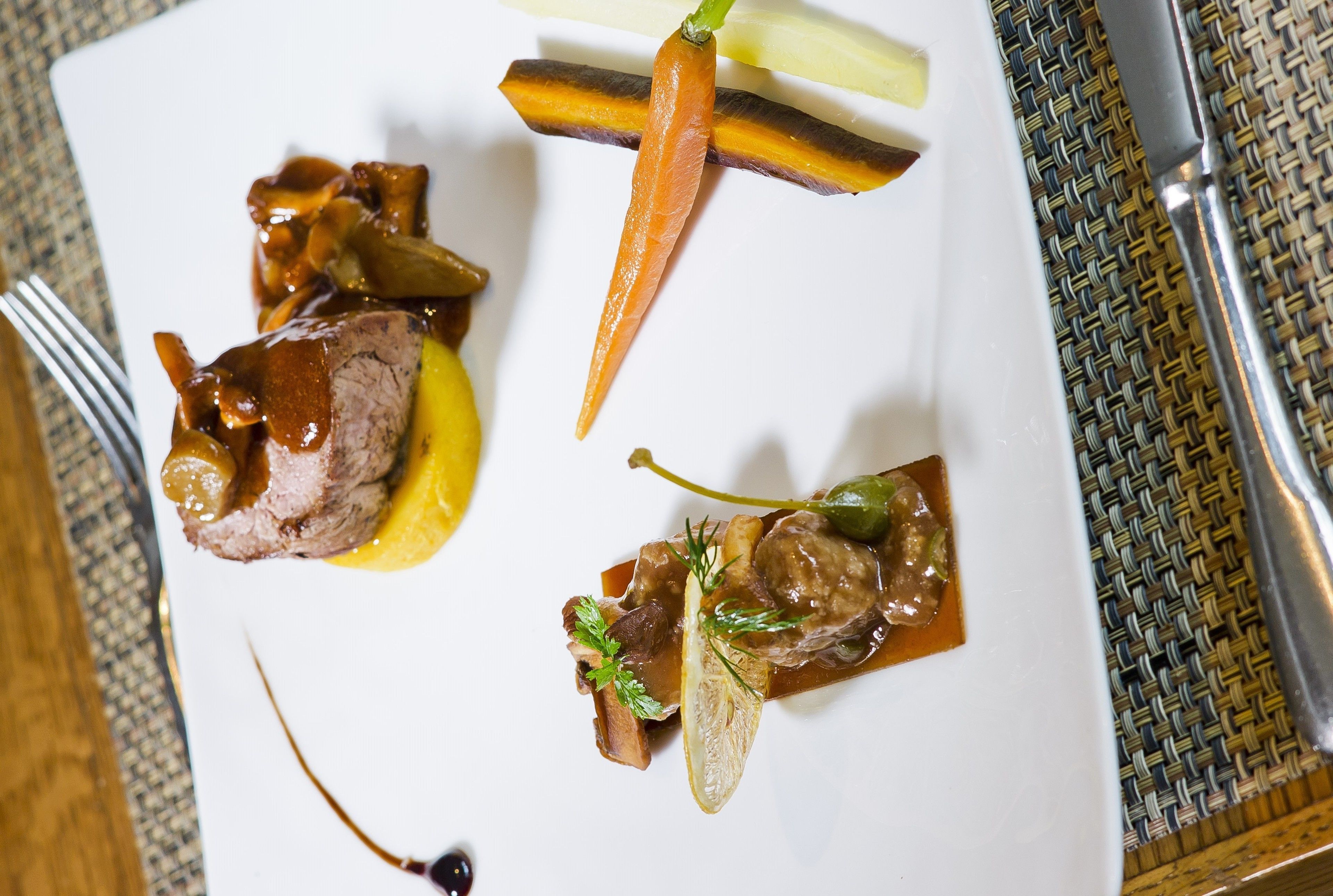 A white plate with various food items including meat, vegetables, and sauces.