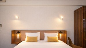 A hotel room with a large bed, two bedside tables with lamps, a wooden wardrobe, and a chair. - The Originals Boutique, Hôtel Auberge du Forgeron, Lille Sud (Seclin)