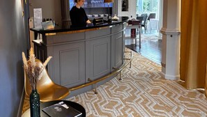 A hotel lobby with a reception desk, a bar area, and a seating area with a patterned carpet. - The Originals Boutique, Hôtel Auberge du Forgeron, Lille Sud (Seclin)