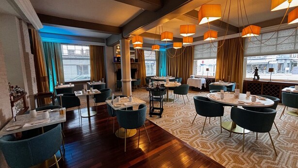 A restaurant with wooden floors, blue chairs, and orange pendant lights. Tables are set with white tablecloths and silverware. - The Originals Boutique, Hôtel Auberge du Forgeron, Lille Sud (Seclin)