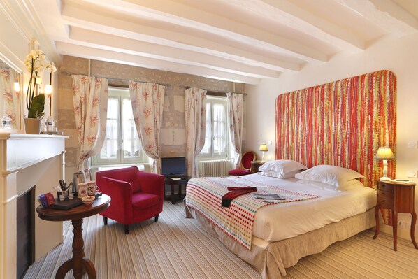 A hotel room with a bed, a red chair, a small table with a lamp, and a television. - Auberge du Bon Laboureur (Chenonceaux)