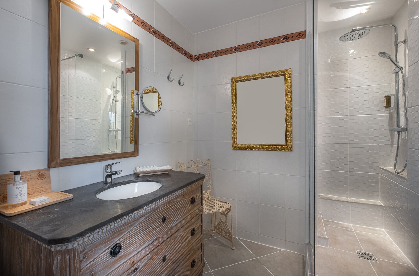 Un baño con dos lavamanos, un espejo grande, ducha y tocador de madera.
