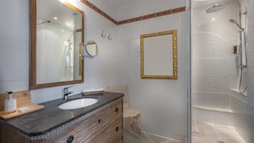 Un baño con dos lavamanos, un espejo grande, ducha y tocador de madera.