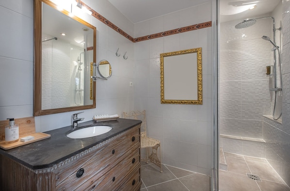 A bathroom with two sinks, a large mirror, a shower, and a wooden vanity.