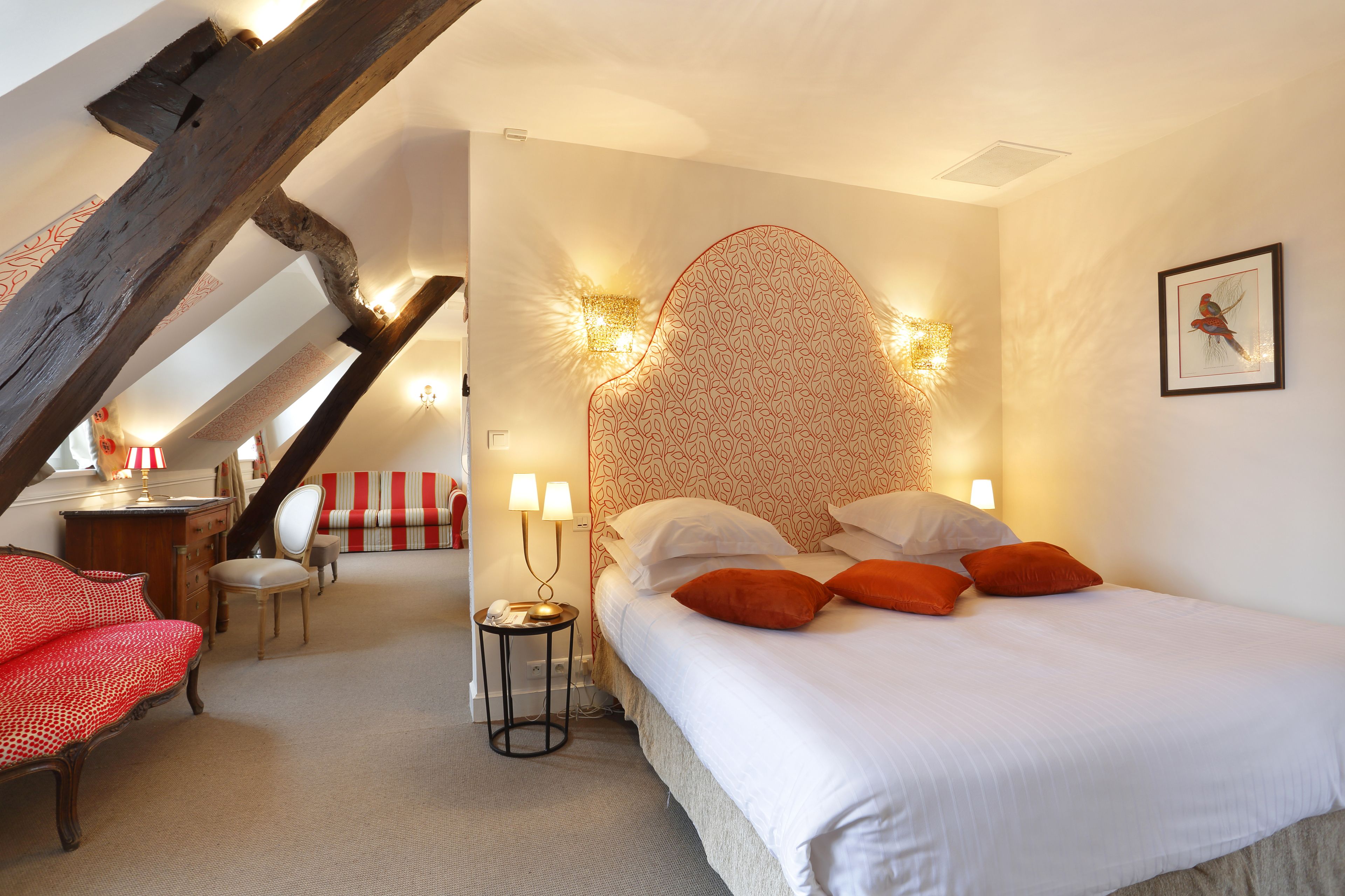 Une chambre à coucher avec un lit, deux lampes de chevet, une chaise, un bureau et un canapé rayé rouge et blanc.