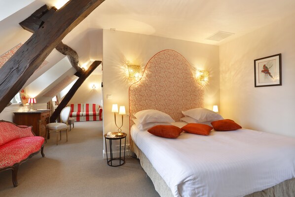 Une chambre à coucher avec un lit, deux lampes de chevet, une chaise, un bureau et un canapé rayé rouge et blanc.