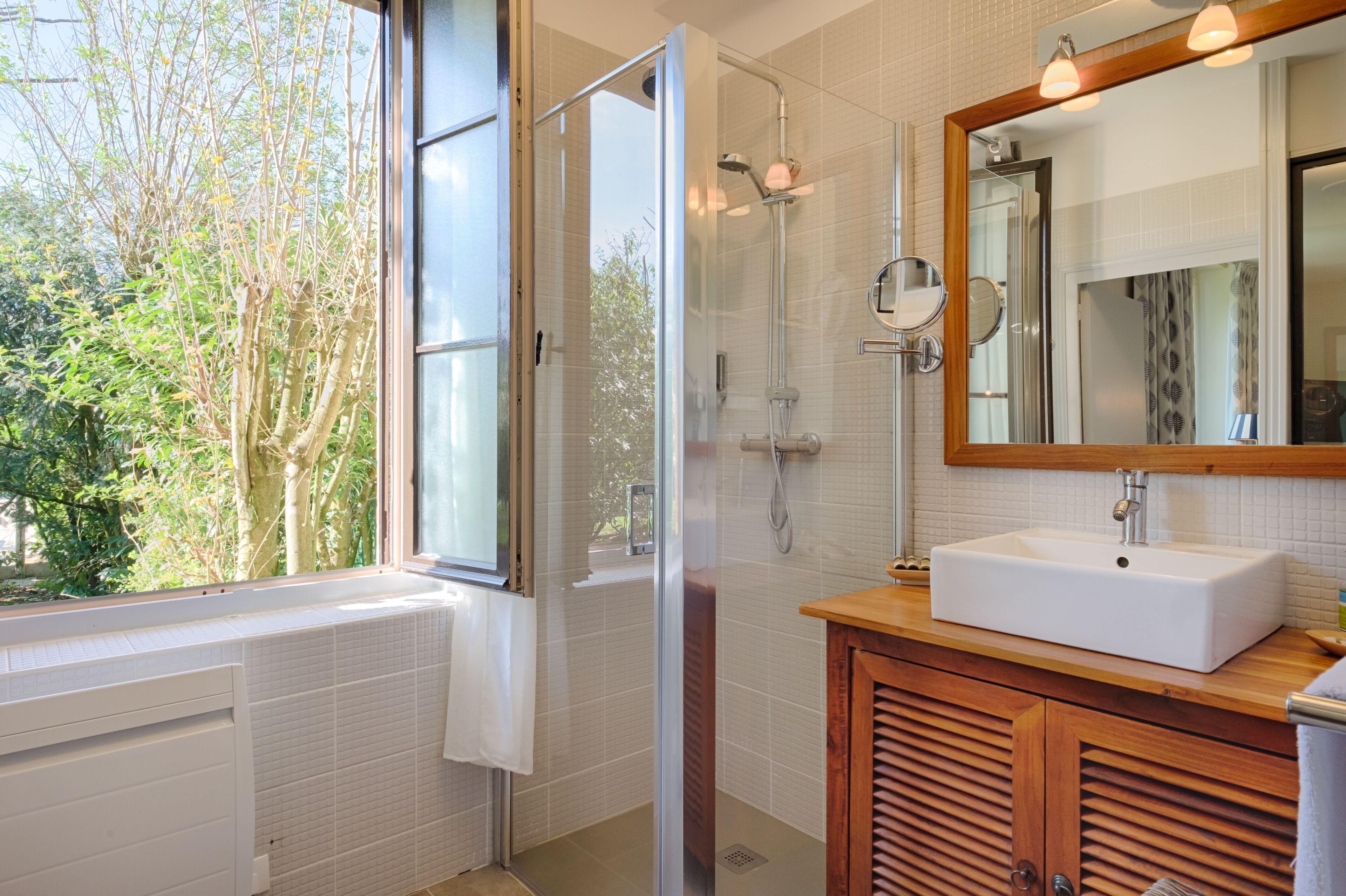 Un baño moderno con cabina de ducha de vidrio, un lavabo blanco y un espejo grande.