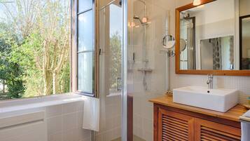 Un baño moderno con cabina de ducha de vidrio, un lavabo blanco y un espejo grande.