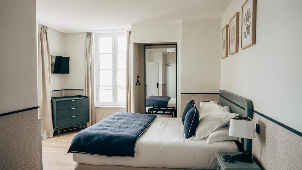 A hotel room with a bed, bedside table, lamp, and a television on the wall.