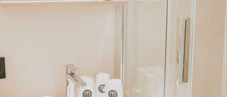 A modern bathroom with a glass shower enclosure, a wooden vanity, and a mirror above the sink.