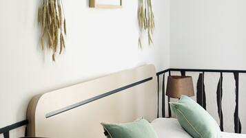 Une chambre à coucher avec un lit, des oreillers, une lampe de chevet et deux plantes fixées au mur.