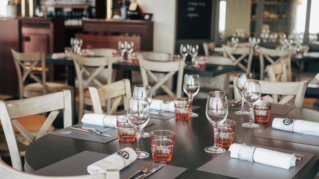 A restaurant setting with tables set for dining, complete with cutlery and glasses.