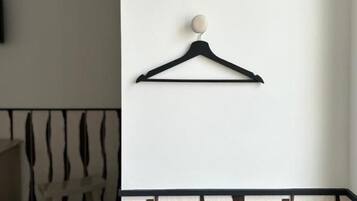 En svart vägghängare med en rund knopp, en andra hängare under den och en väggsektion nedtill med ett mönster.