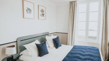 Una camera d'albergo con un letto, un comodino, una lampada e una finestra con tende.