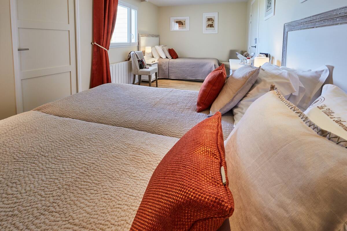 A hotel room with two beds, a desk, and a chair.