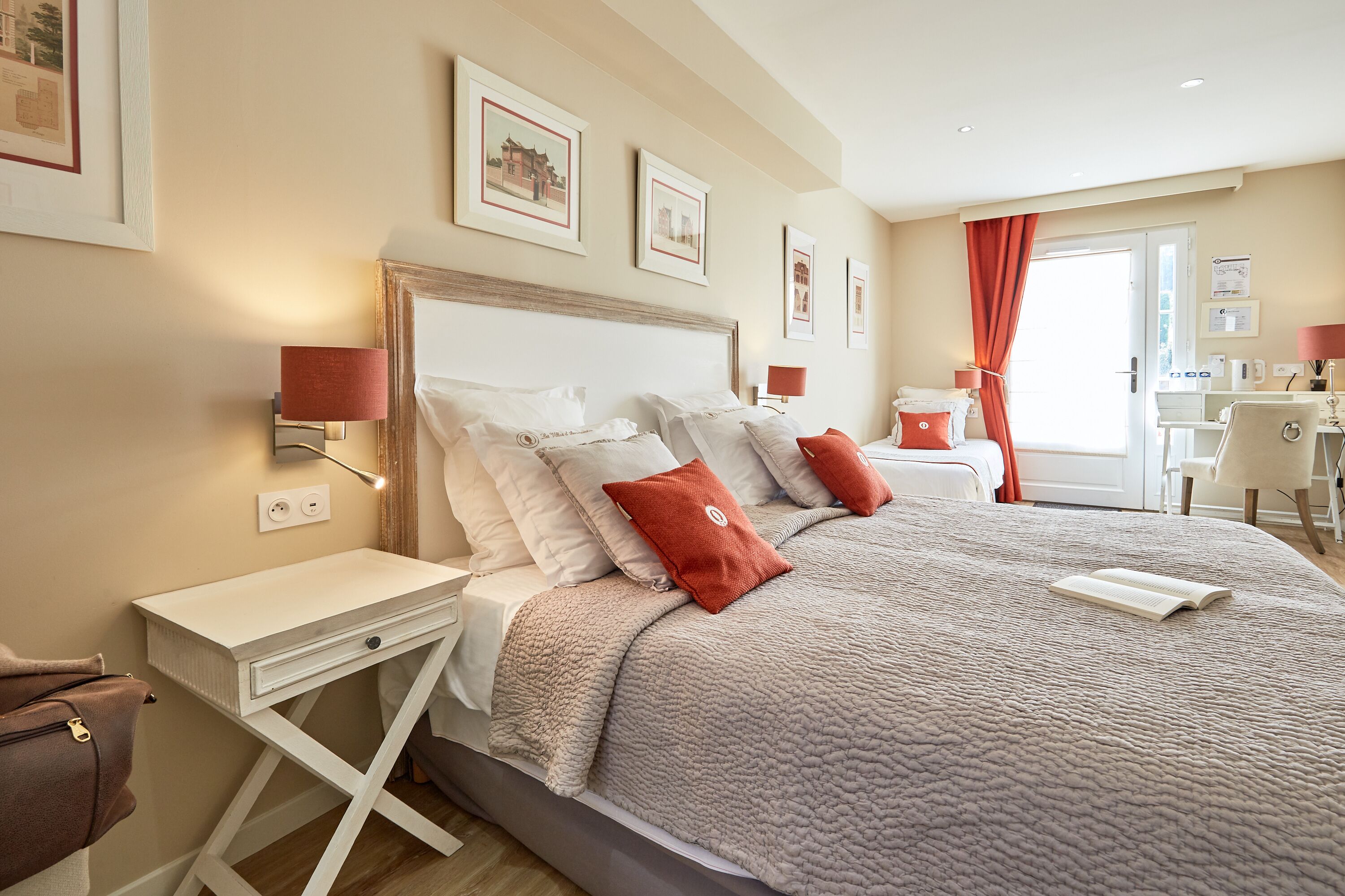 Ein ordentlich eingerichtetes Hotelzimmer mit einem großen Bett, Nachttischen, einem Schreibtisch und einem Sessel.