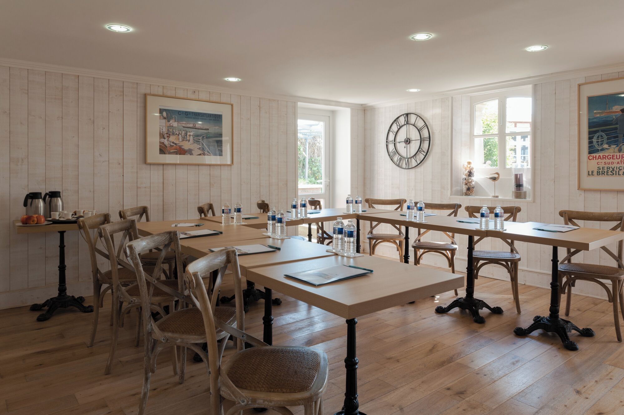 Une salle de conférence aux murs lambrés, avec une grande horloge murale et des tables disposées pour les réunions.