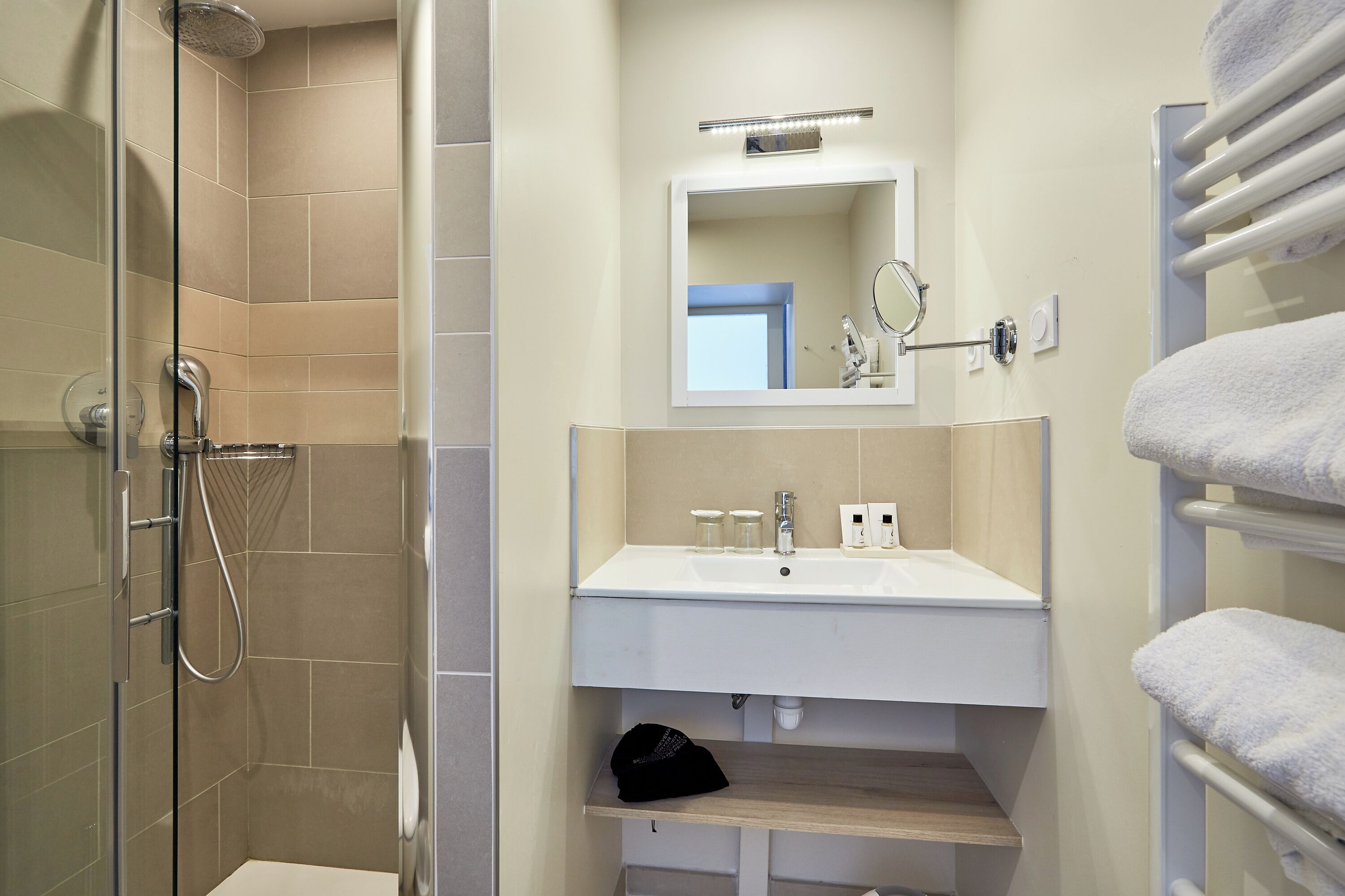 A modern bathroom with a glass-enclosed shower, a white sink, and a mirror above it.