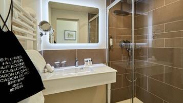 A modern bathroom with a white sink, a mirror, and a shower area.