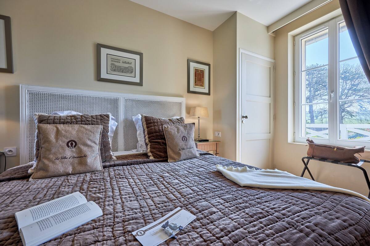A neatly made bed with a quilted bedspread, two pillows, and a bedside table with a lamp.