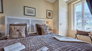 A neatly made bed with a quilted bedspread, two pillows, and a bedside table with a lamp.