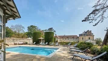A swimming pool with lounge chairs and a large building in the background.