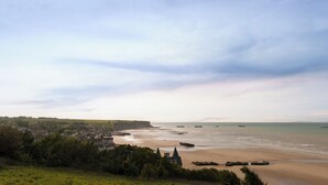 A coastal town with a sandy beach, a cliff, and a view of the sea.