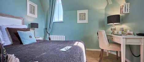 Un dormitorio con una cama, un escritorio y una silla. Hay dos cuadros en la pared.