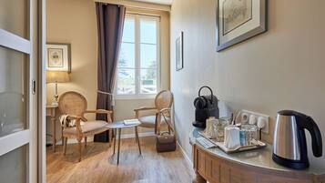 Une pièce chaleureuse avec un plancher en bois, deux fauteuils en osier, une petite table avec un livre, une lampe, une bouilloire et un plateau avec des verres et une cafetière.