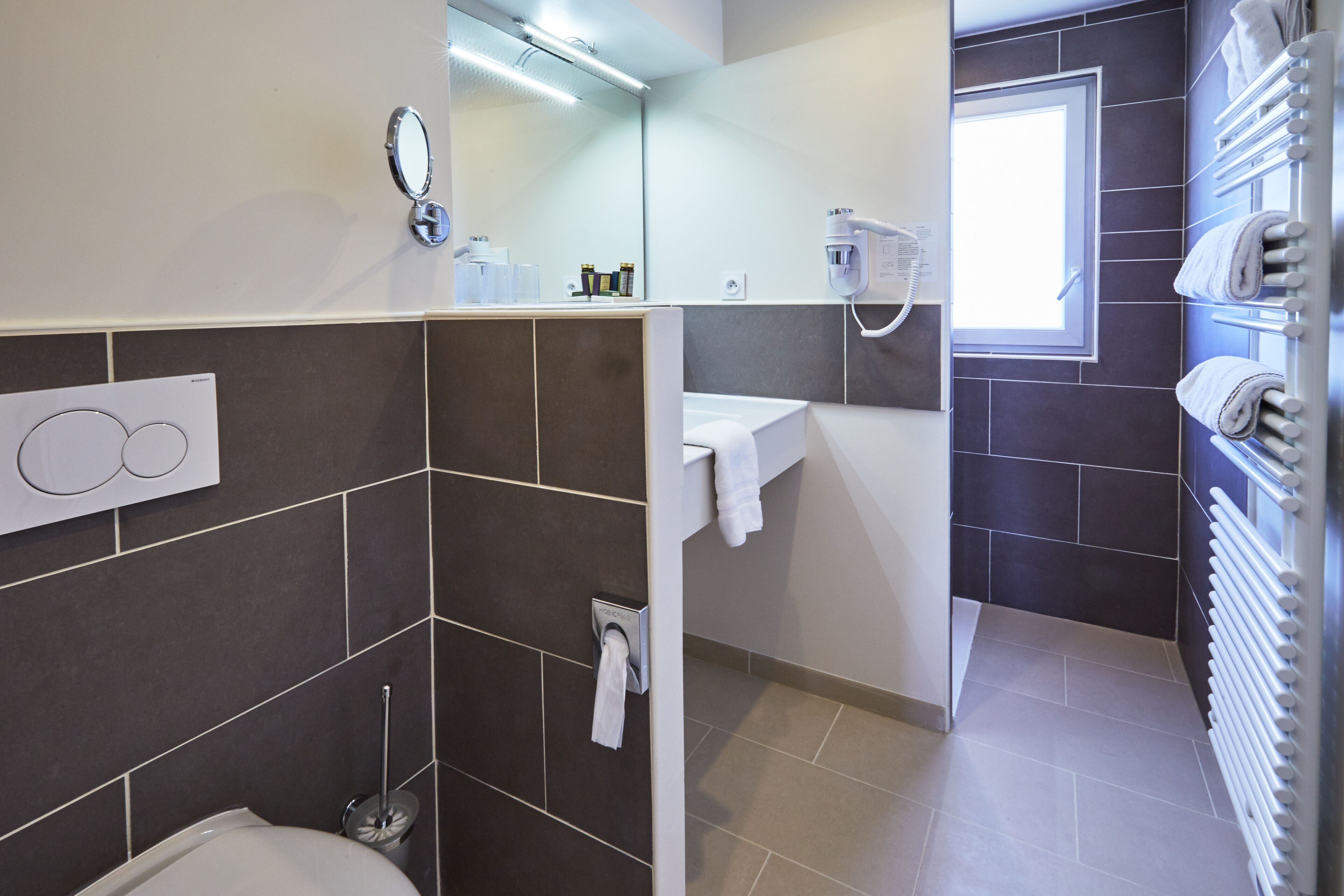 A modern bathroom with a toilet, a sink, a mirror, and a towel rack.