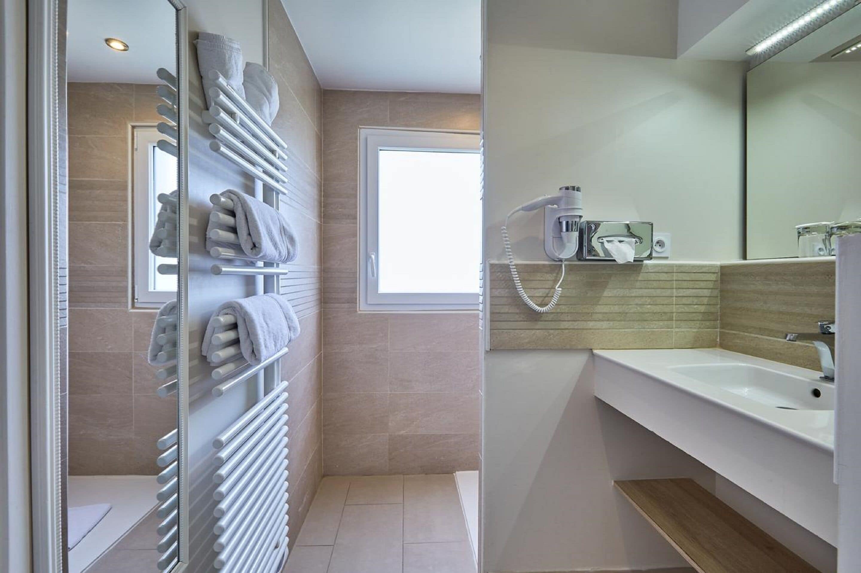 Un baño moderno con toallero, ducha, lavamanos y espejo.