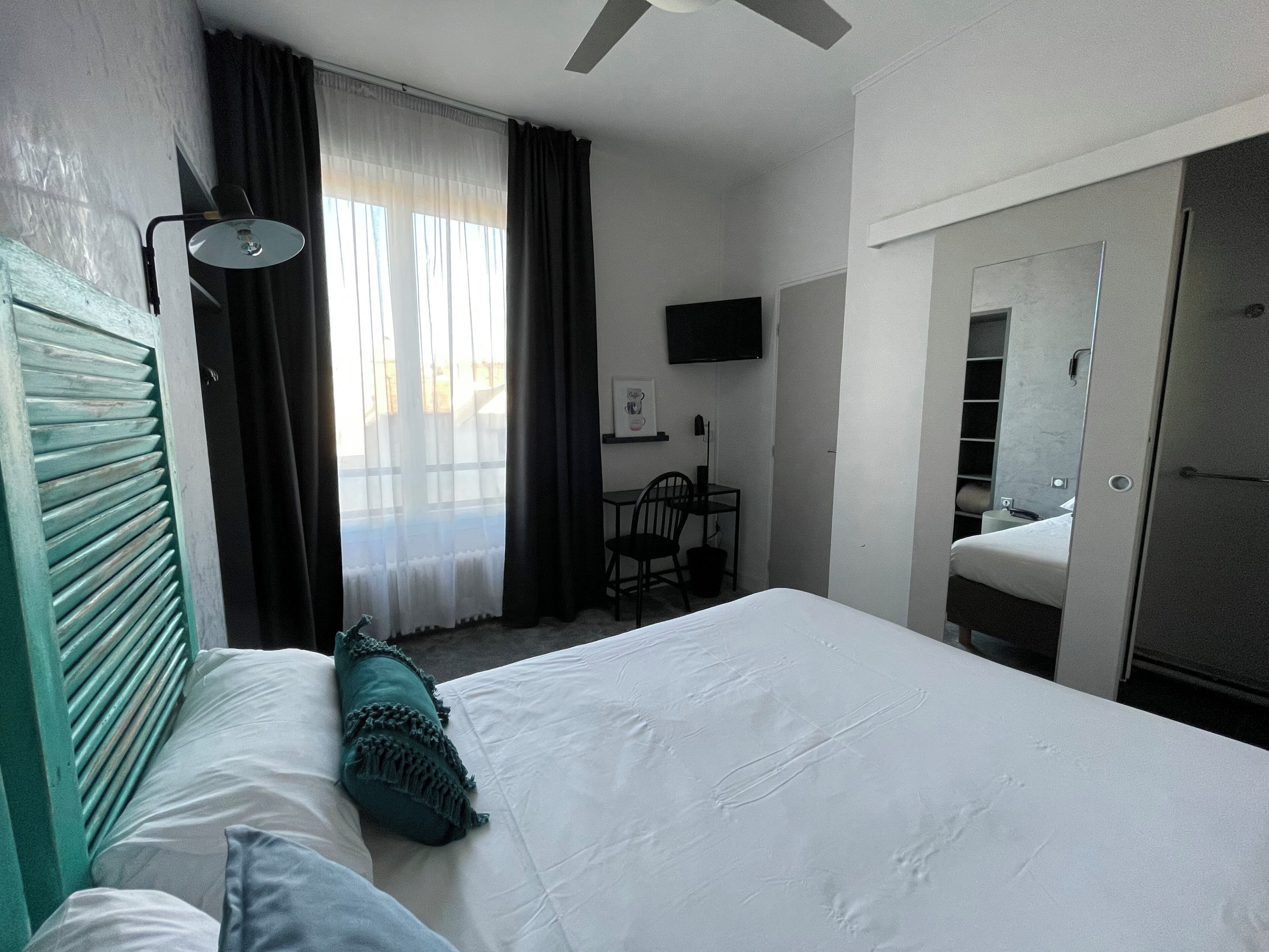 Een hotelkamer met een bed, bureau, stoel, televisie en kledingkast.